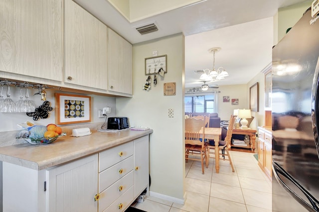 kitchen with decorative light fixtures, refrigerator, light tile patterned flooring, and an inviting chandelier