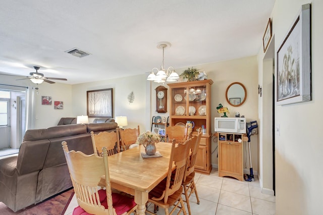 tiled dining room with ceiling fan with notable chandelier