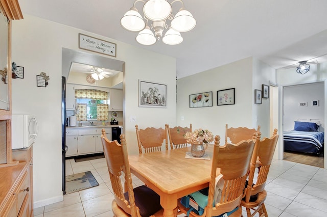 dining space with ceiling fan with notable chandelier, sink, and light tile patterned floors