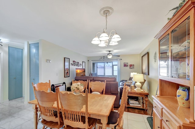 tiled dining room with ceiling fan with notable chandelier