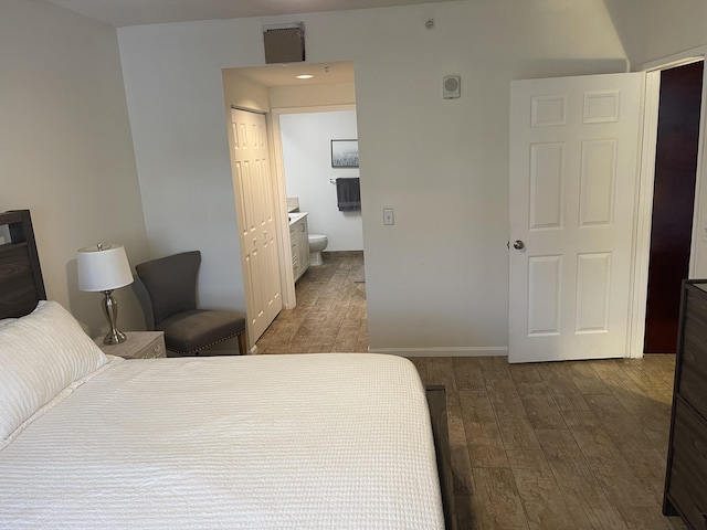 bedroom with dark hardwood / wood-style flooring, ensuite bath, and a closet