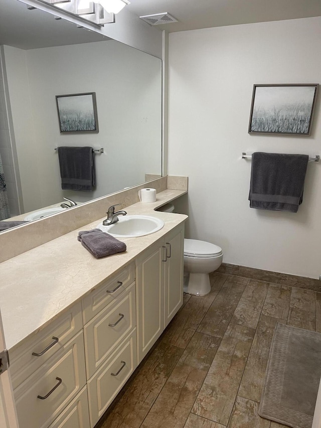 bathroom featuring vanity, hardwood / wood-style floors, and toilet