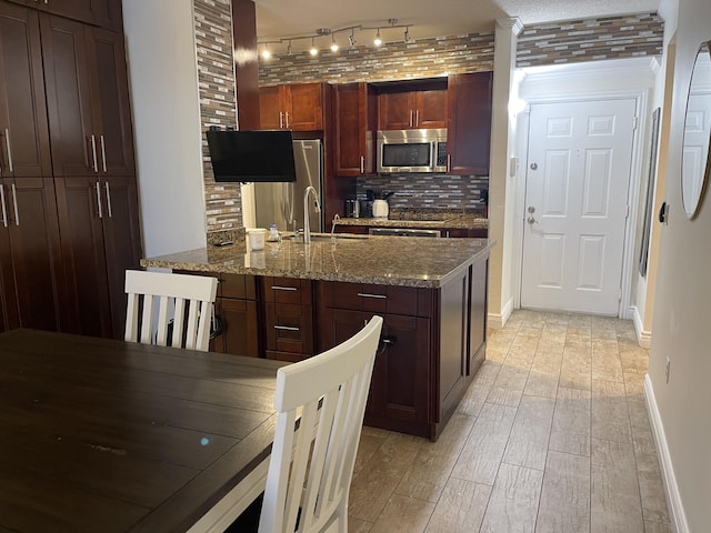 kitchen featuring sink, backsplash, light stone counters, stainless steel appliances, and light wood-type flooring