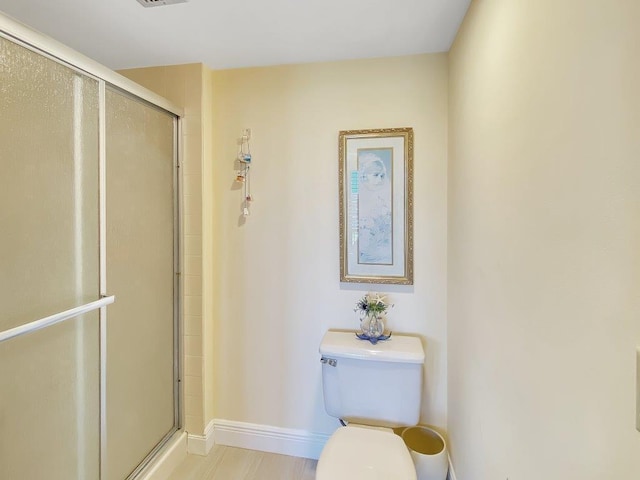 bathroom featuring toilet and an enclosed shower