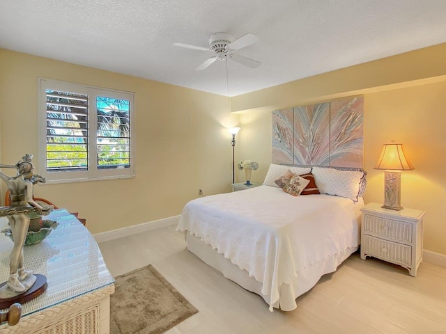 bedroom with ceiling fan, a textured ceiling, and light hardwood / wood-style floors