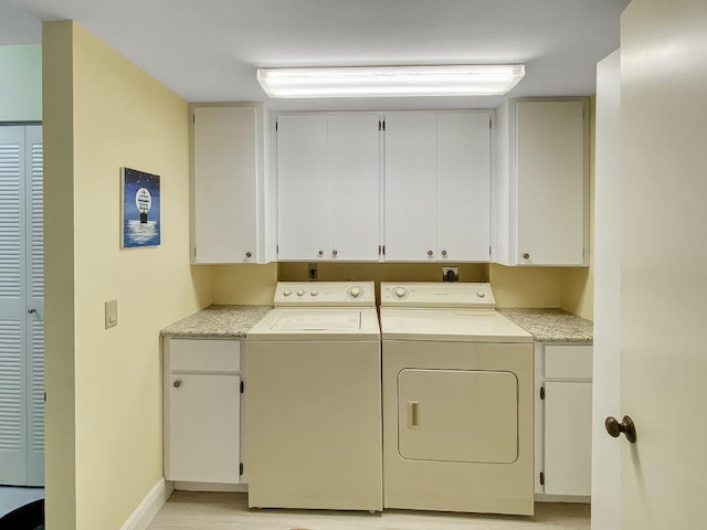 clothes washing area with cabinets and washing machine and clothes dryer