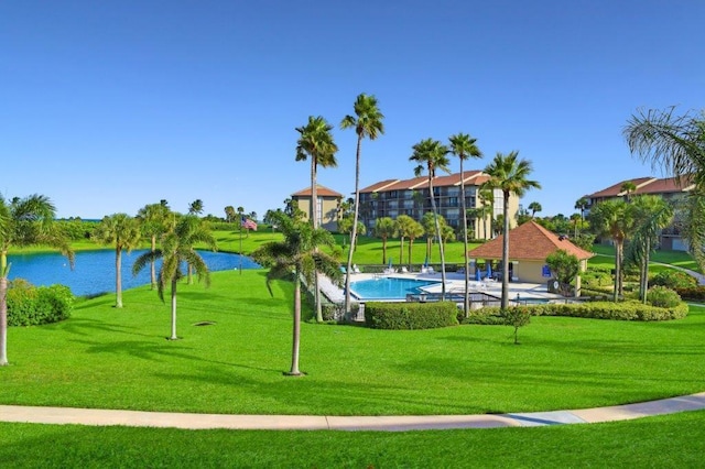 view of property's community with a water view, a yard, and a swimming pool