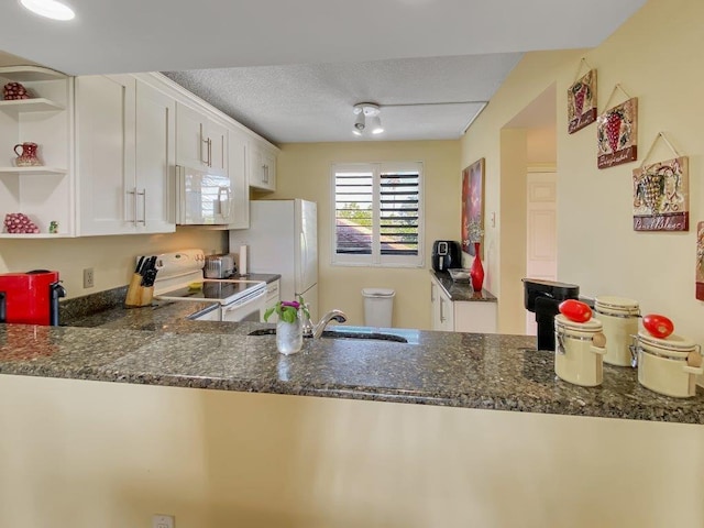 kitchen featuring white cabinetry, white appliances, a textured ceiling, and dark stone countertops