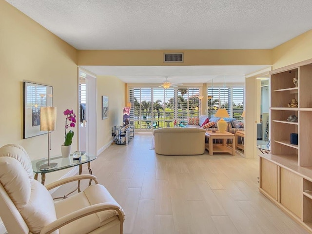 living room featuring ceiling fan and a textured ceiling