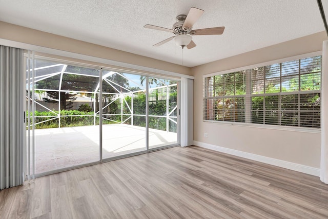 empty room featuring ceiling fan, light hardwood / wood-style flooring, and a textured ceiling