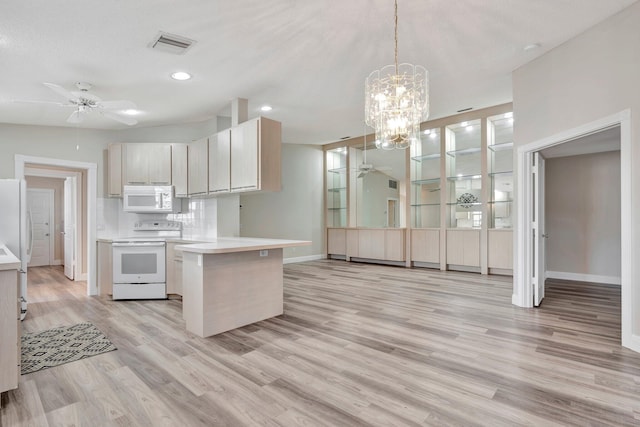 kitchen with decorative light fixtures, white appliances, and light hardwood / wood-style floors