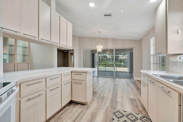 kitchen with light hardwood / wood-style flooring, kitchen peninsula, pendant lighting, a textured ceiling, and vaulted ceiling