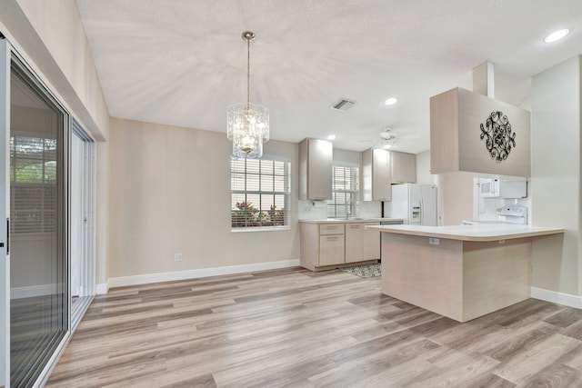 kitchen with ceiling fan with notable chandelier, light hardwood / wood-style floors, white appliances, and kitchen peninsula