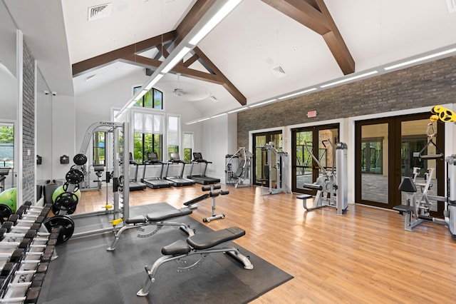 exercise room with french doors, brick wall, ceiling fan, hardwood / wood-style flooring, and high vaulted ceiling