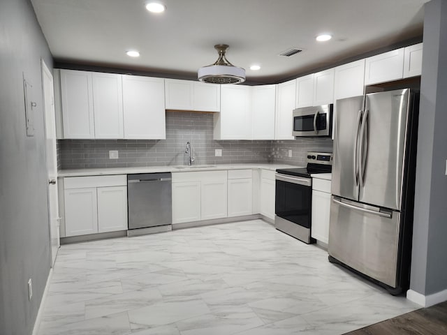 kitchen featuring appliances with stainless steel finishes, white cabinetry, backsplash, and sink