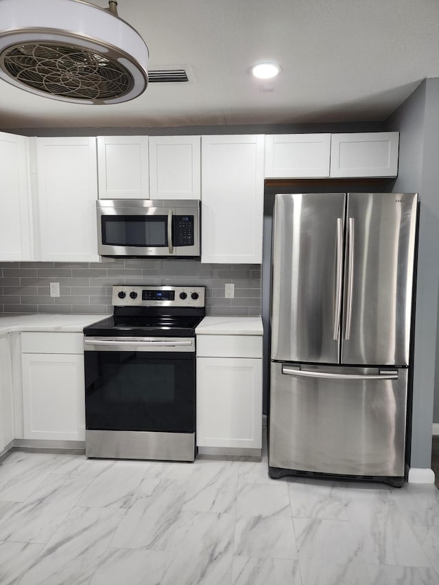 kitchen with white cabinets, appliances with stainless steel finishes, and backsplash