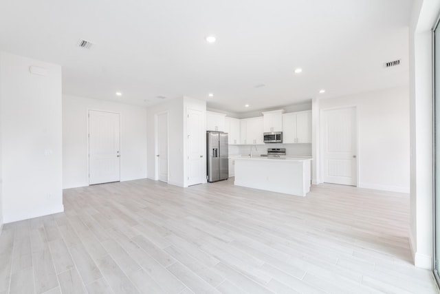 unfurnished living room with sink and light hardwood / wood-style flooring