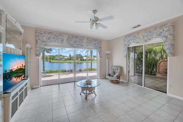 living area featuring ceiling fan, a water view, light tile patterned floors, and ornamental molding