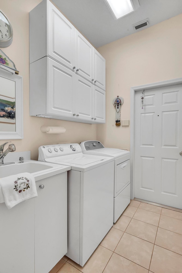 clothes washing area with cabinets, sink, washing machine and clothes dryer, and light tile patterned flooring