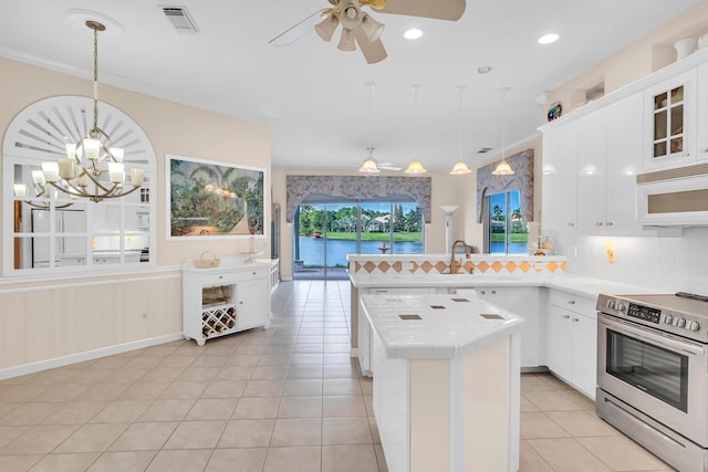 kitchen featuring white cabinetry, hanging light fixtures, crown molding, stainless steel range with electric stovetop, and light tile patterned floors