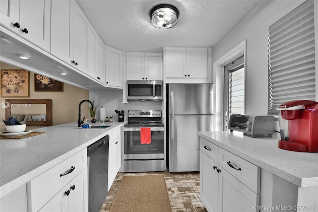 kitchen featuring sink, appliances with stainless steel finishes, light stone countertops, and white cabinets