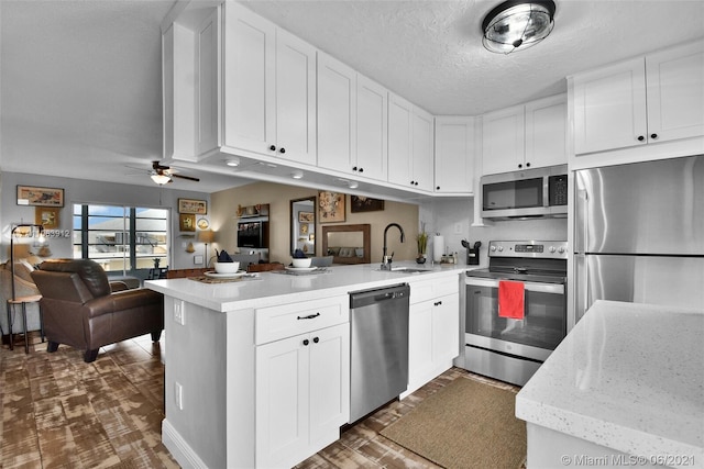 kitchen featuring a textured ceiling, white cabinets, ceiling fan, stainless steel appliances, and sink