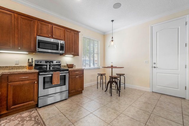 kitchen with appliances with stainless steel finishes, hanging light fixtures, light tile patterned floors, crown molding, and light stone countertops