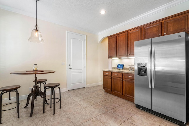 kitchen with light tile patterned floors, a textured ceiling, pendant lighting, stainless steel refrigerator with ice dispenser, and ornamental molding