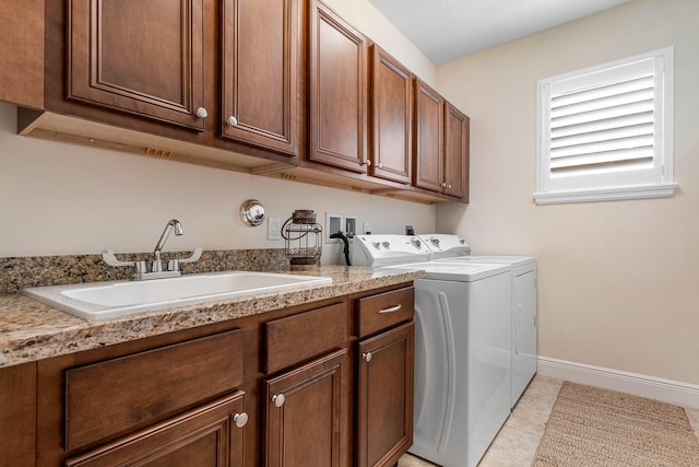 laundry area featuring light tile patterned flooring, washing machine and clothes dryer, cabinets, and sink