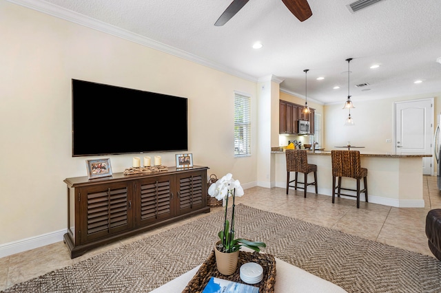 living room featuring ornamental molding, a textured ceiling, light tile patterned floors, and ceiling fan