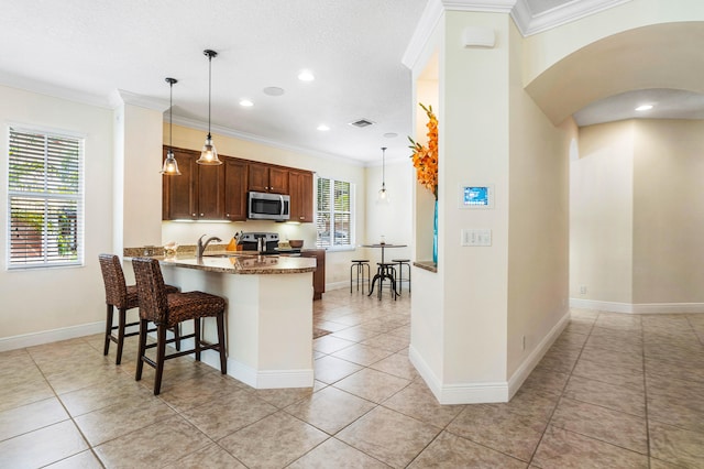 kitchen featuring a breakfast bar area, decorative light fixtures, appliances with stainless steel finishes, and light tile patterned floors