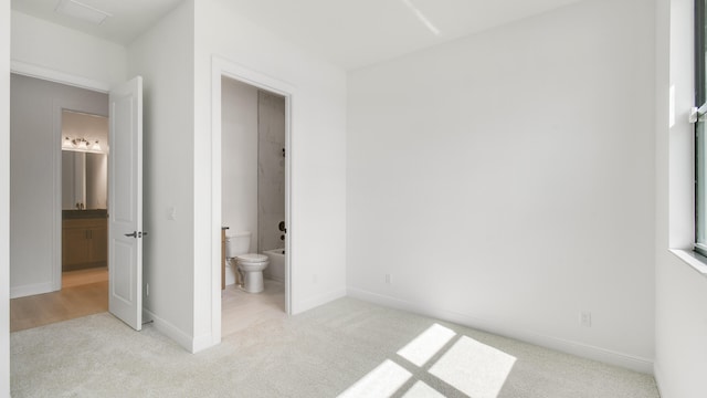 bedroom with ensuite bathroom and light colored carpet