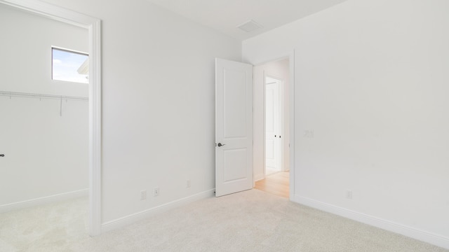 unfurnished bedroom with light carpet and a closet