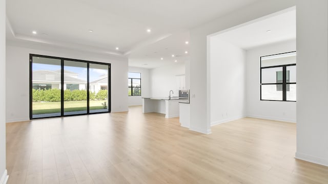 unfurnished living room featuring sink and light wood-type flooring