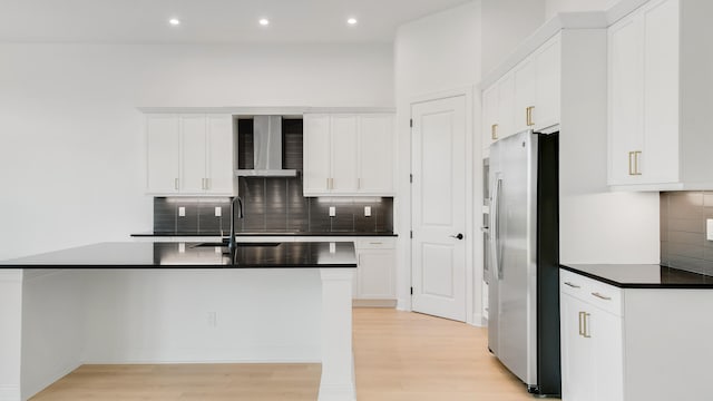 kitchen with sink, backsplash, stainless steel fridge, white cabinets, and light hardwood / wood-style flooring