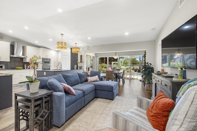 living room with sink, vaulted ceiling, and light wood-type flooring