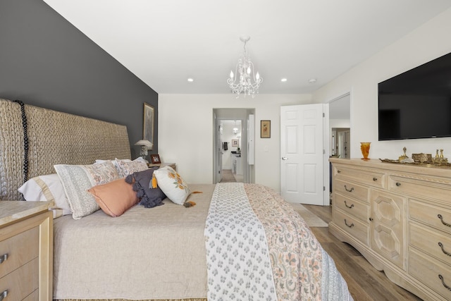 bedroom featuring connected bathroom, a chandelier, and light hardwood / wood-style flooring