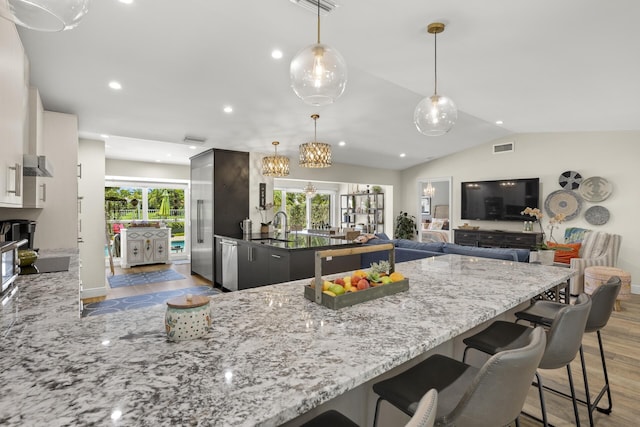 kitchen with a breakfast bar, white cabinetry, lofted ceiling, sink, and light stone counters