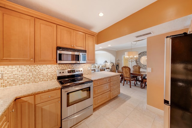 kitchen with light brown cabinetry, tasteful backsplash, stainless steel appliances, an inviting chandelier, and light tile patterned floors