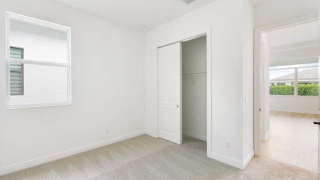 unfurnished bedroom with light carpet and a closet