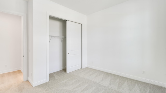 unfurnished bedroom featuring a closet and light colored carpet