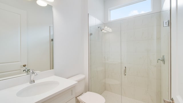 bathroom with a shower with door, vanity, and toilet