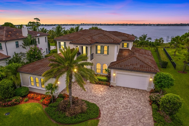 mediterranean / spanish-style house featuring a garage and a water view