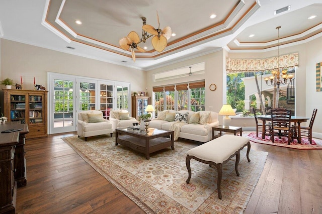 living room featuring ceiling fan with notable chandelier, hardwood / wood-style flooring, and a raised ceiling