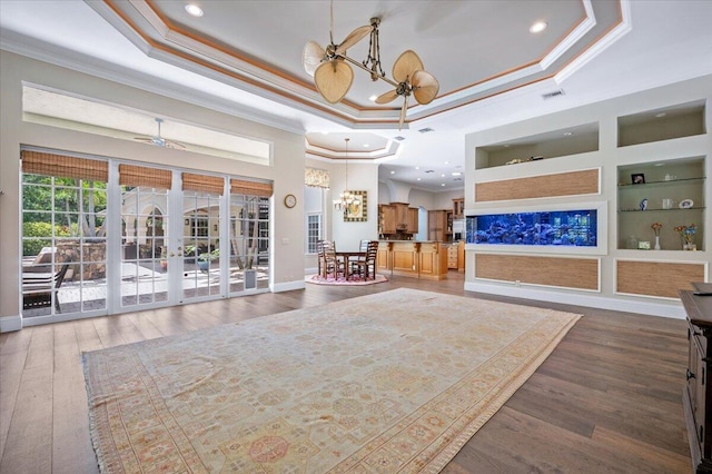 interior space with a raised ceiling, built in features, and crown molding