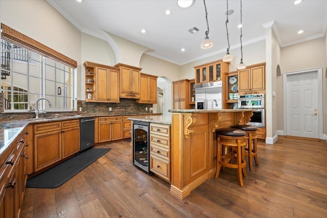 kitchen featuring sink, a center island, beverage cooler, light stone counters, and appliances with stainless steel finishes