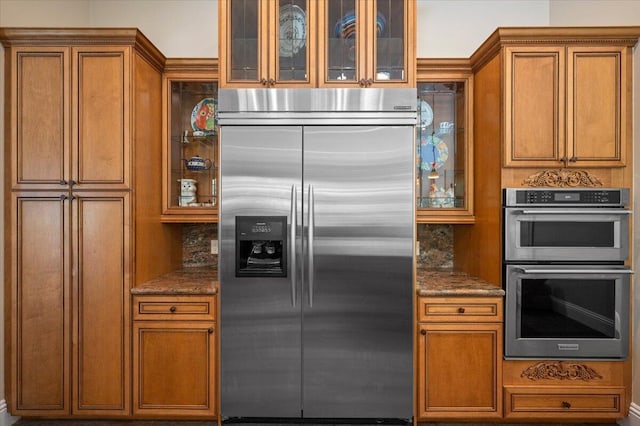 kitchen featuring backsplash, dark stone counters, and appliances with stainless steel finishes