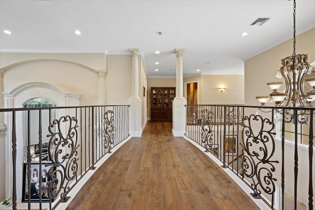 hall featuring hardwood / wood-style floors, a chandelier, ornamental molding, and decorative columns