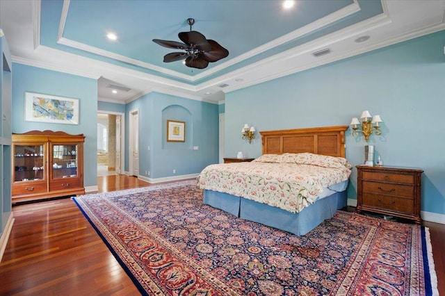 bedroom featuring a tray ceiling, ceiling fan, dark hardwood / wood-style floors, and ornamental molding