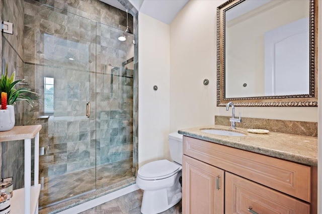 bathroom featuring tile patterned floors, vanity, toilet, and a shower with shower door